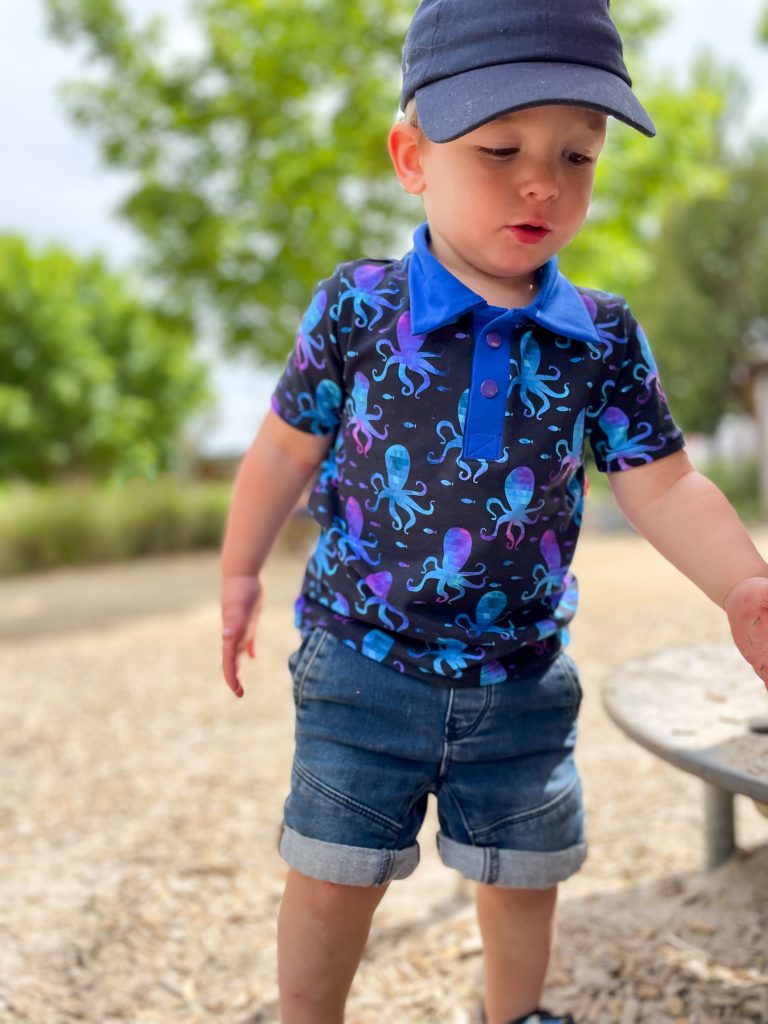 little boy in dark blue polo shirt with octopus print looking down